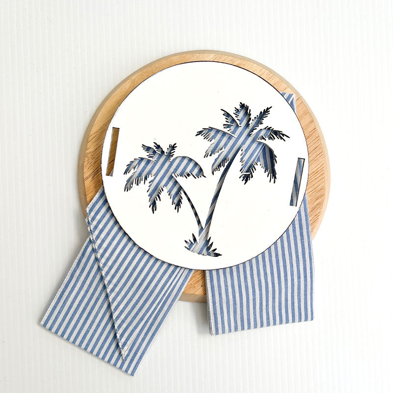 Stone colour coastal cushion with blue and white stripe sash. A tropical inspired cushion with the palm tree motive can be used in your costal home. Timber Palm Disk