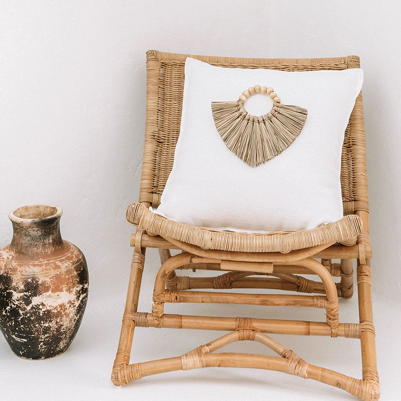 White boho cushion featuring a boho decoration made of seagrass and timber beads. Natural décor.