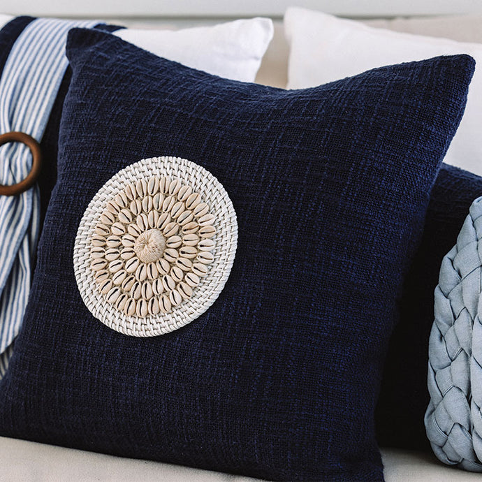 Navy blue coastal cushion with a rattan and shell disk, the perfect beach pillows for your coastal home.