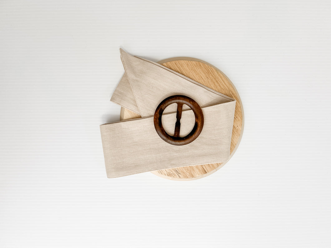 white 100% cotton cushion cover with the option of a generous feather insert. Wrapped around the cushion is a stone colour Buckle Sash and small Timber Buckle. Classic style cushion
