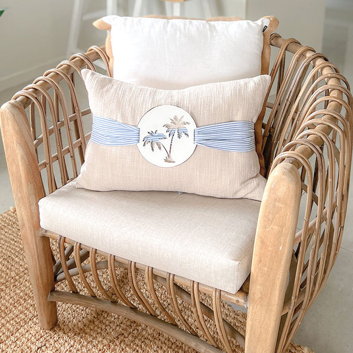 Stone colour coastal cushion with blue and white stripe sash. A tropical inspired cushion with the palm tree motive can be used in your costal home.